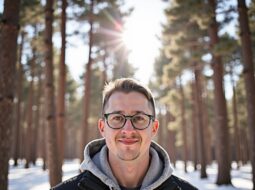 Dr. Connor Robertson smiling in green winter coat with fur hood in snowy forest